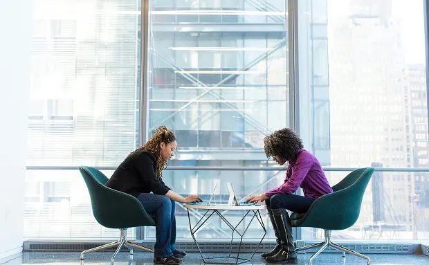 Two women sitting at a table on their laptops